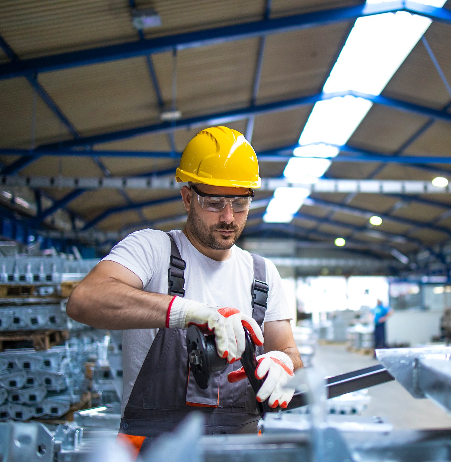 Factory worker working in industrial production hall.
